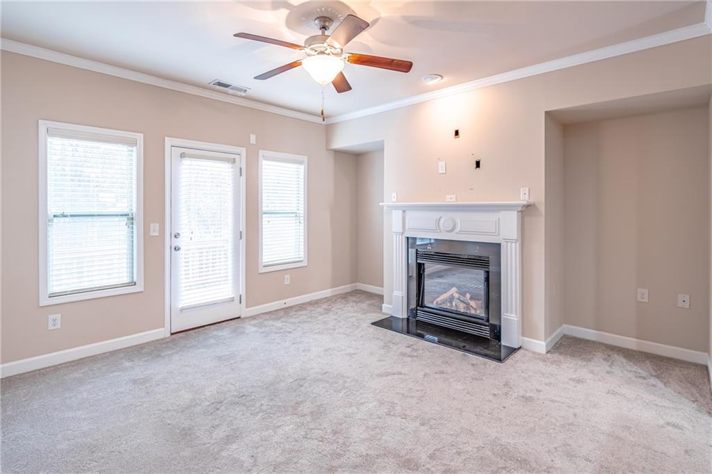 Unfurnished living room featuring light colored carpet, ceiling fan, and a wealth of natural light Unfurnished living room featuring light colored carpet, ceiling fan, and a wealth of natural light