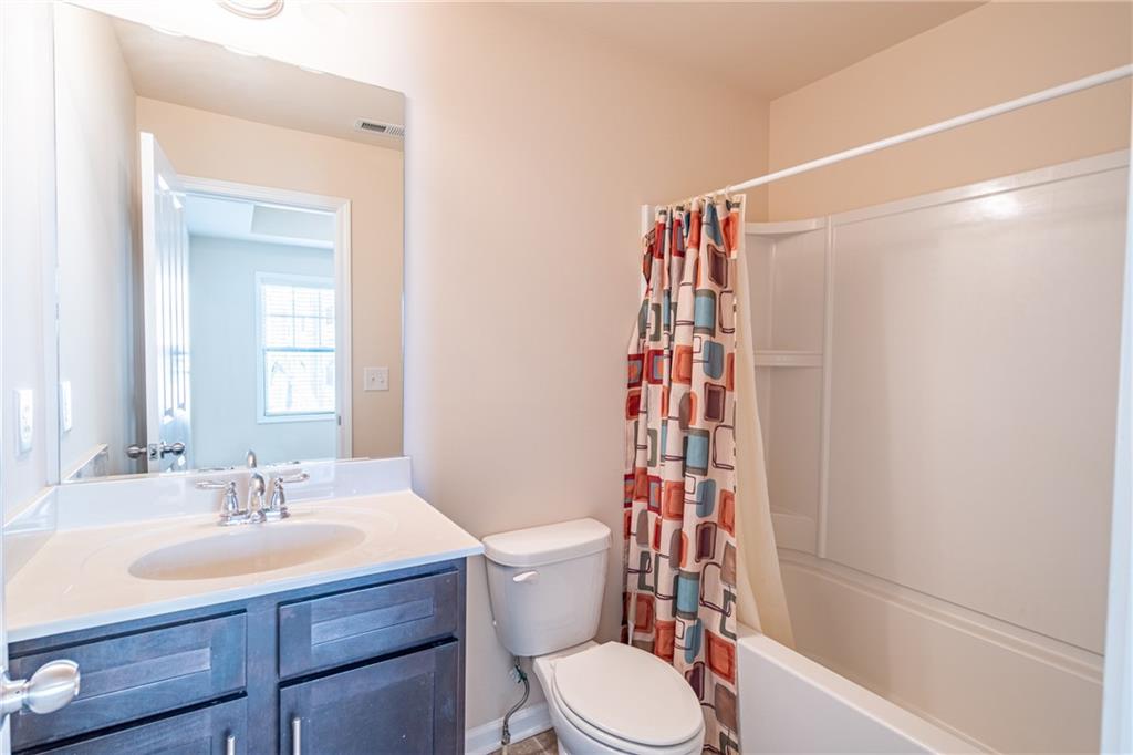 Full bathroom featuring toilet, shower / bathtub combination with curtain, and vanity Full bathroom featuring toilet, shower / bathtub combination with curtain, and vanity