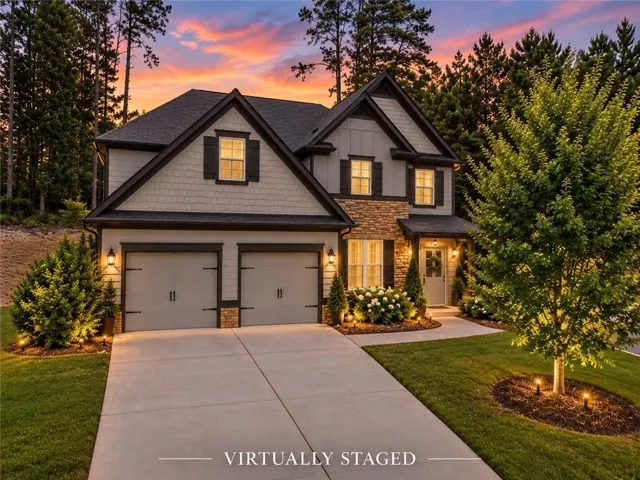 Two-car garage, stone and shingle siding, concrete driveway, landscaped front yard, and an inviting entry porch