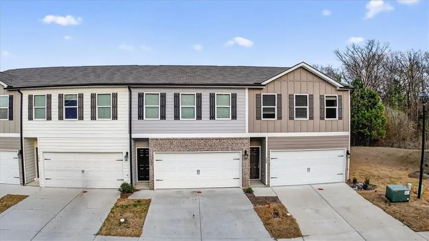 Traditional-style home featuring an attached garage, driveway, and a shingled roof