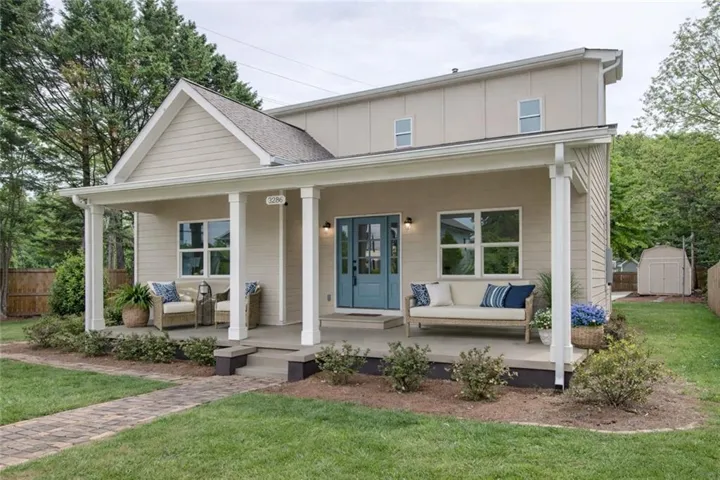 Inviting front porch with white columns, a vibrant blue entry door, and light-colored siding