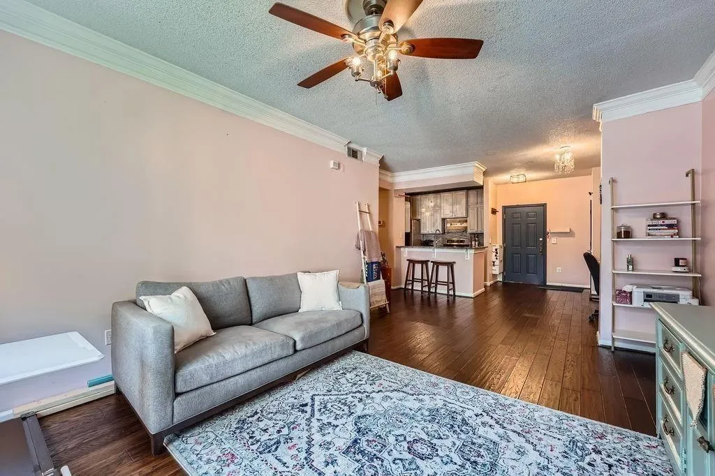Living room with ornamental molding, a textured ceiling, dark wood-style flooring, and ceiling fan