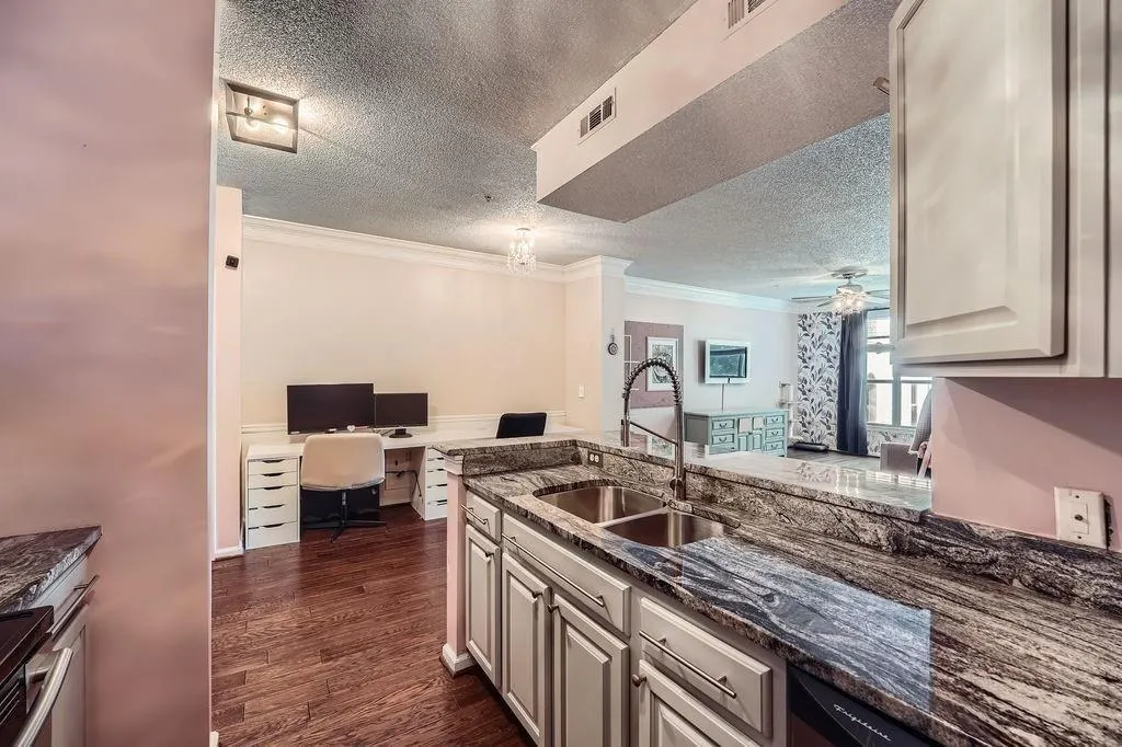 Kitchen with open floor plan, ornamental molding, a textured ceiling, dark wood-type flooring, and dark stone countertops