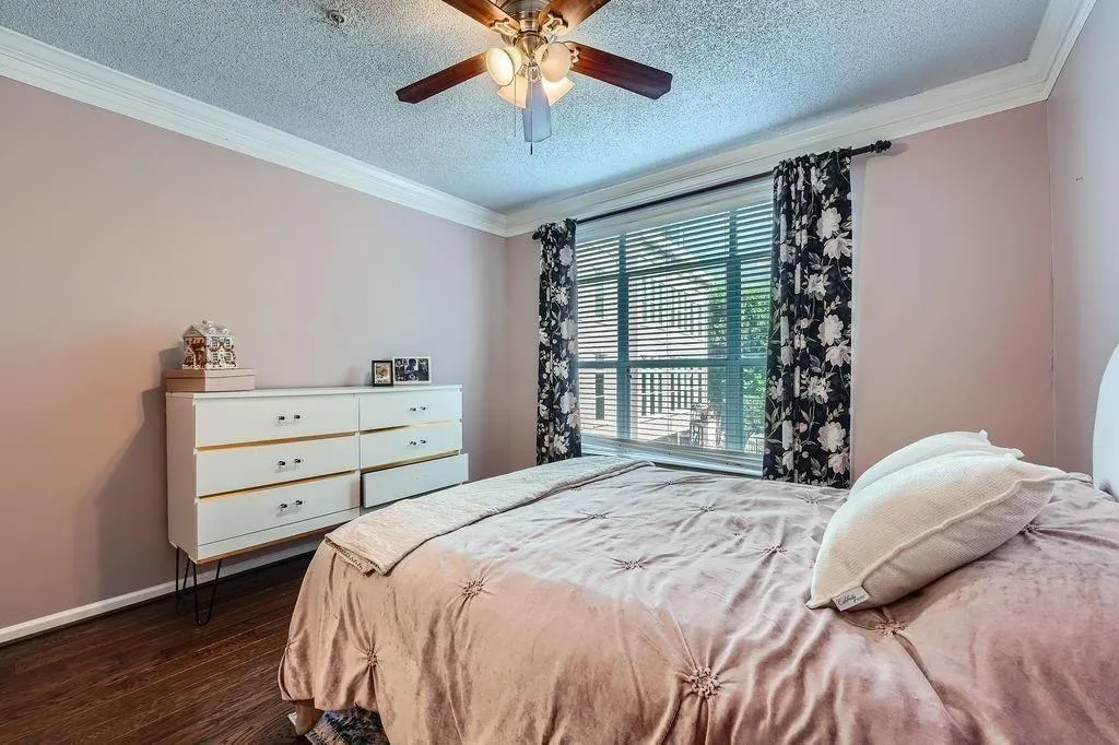 Bedroom featuring dark wood-style flooring, ornamental molding, a textured ceiling, and a ceiling fan