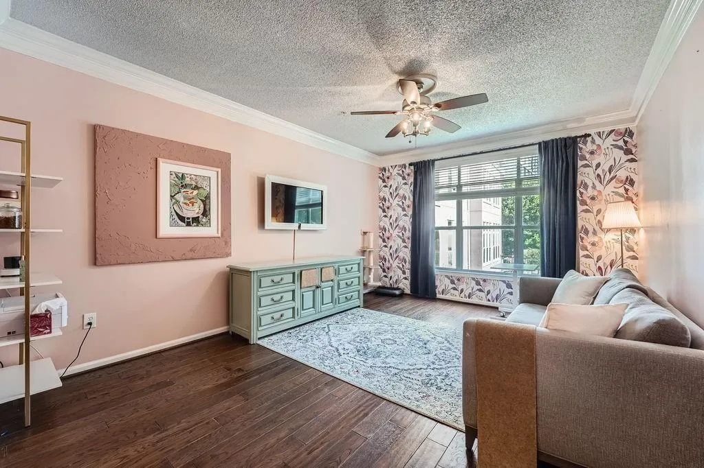 Living room with ornamental molding, a ceiling fan, a textured ceiling, and dark wood-type flooring