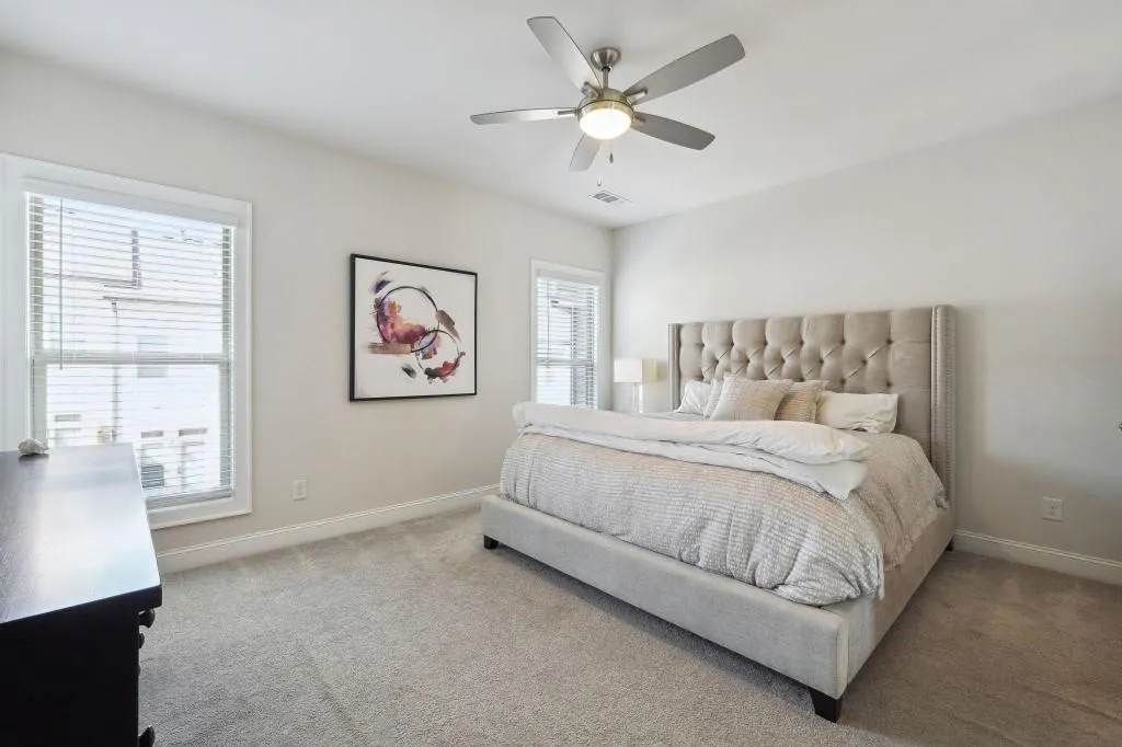 Bedroom featuring light carpet, ceiling fan, and multiple windows