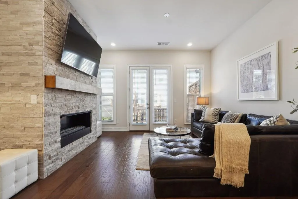 Living room with a stone fireplace, plenty of natural light, and dark hardwood / wood-style floors