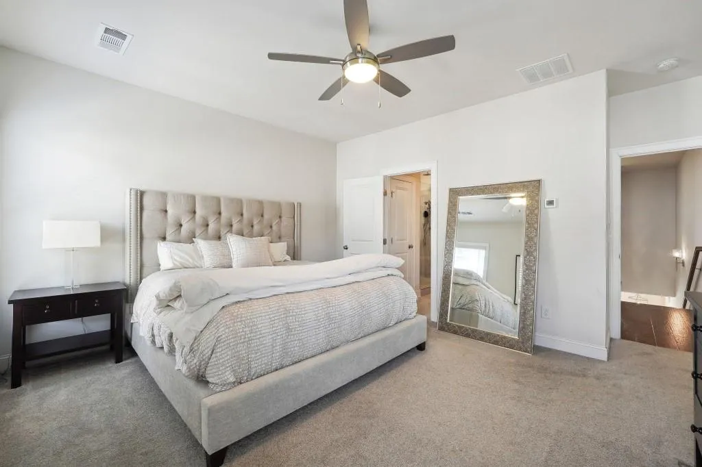 Bedroom with ceiling fan, light carpet, and ensuite bathroom