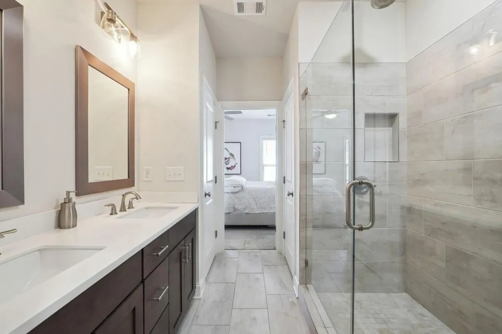 Bathroom with tile flooring, an enclosed shower, and double sink vanity