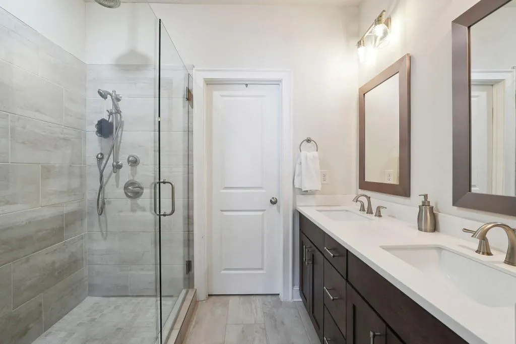 Bathroom with dual sinks, large vanity, and walk in shower