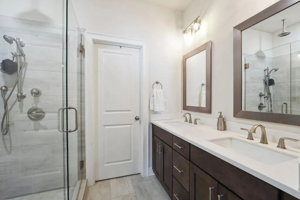 Bathroom featuring a shower with shower door and double sink vanity