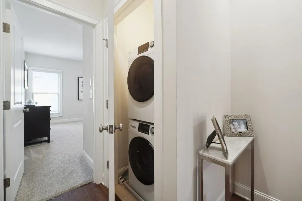 Washroom with light colored carpet and stacked washer and dryer