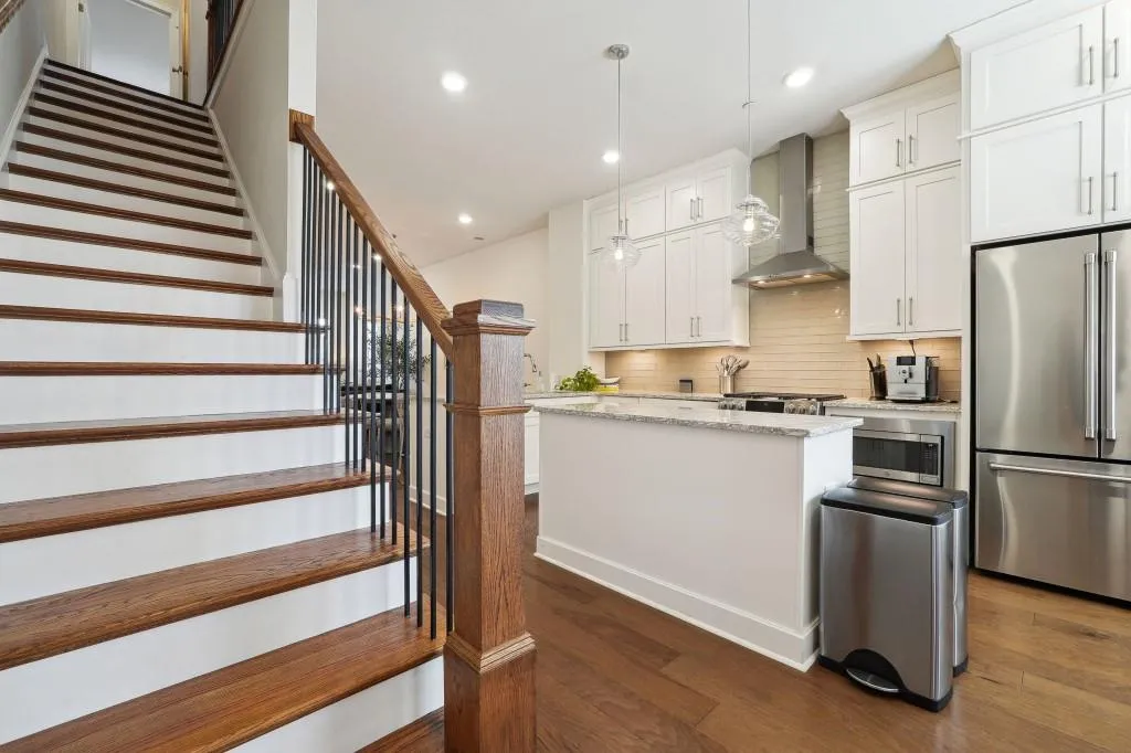 Kitchen with wall chimney exhaust hood, decorative light fixtures, dark wood-type flooring, backsplash, and appliances with stainless steel finishes
