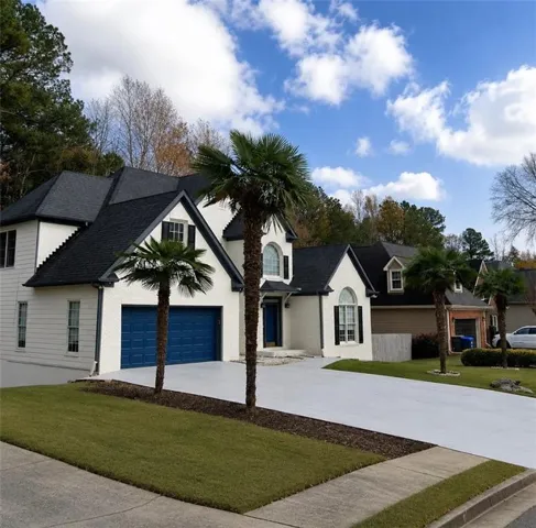 White exterior with dark blue garage doors, a dark shingle roof, and a paved driveway