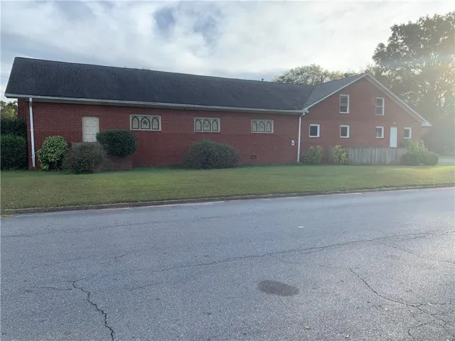 View of home's exterior with brick siding and a lawn