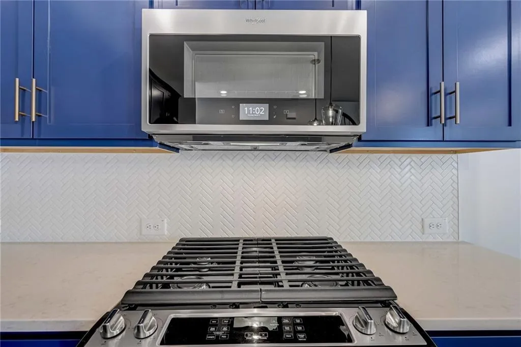 Kitchen view of appliances with stainless steel finishes, blue cabinets, and backsplash