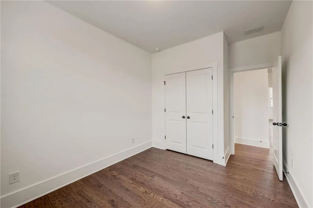 Unfurnished bedroom with dark wood-style flooring and a closet
