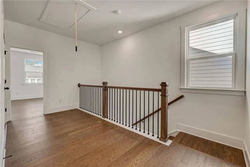 Hallway with attic access, an upstairs landing, wood finished floors, and recessed lighting