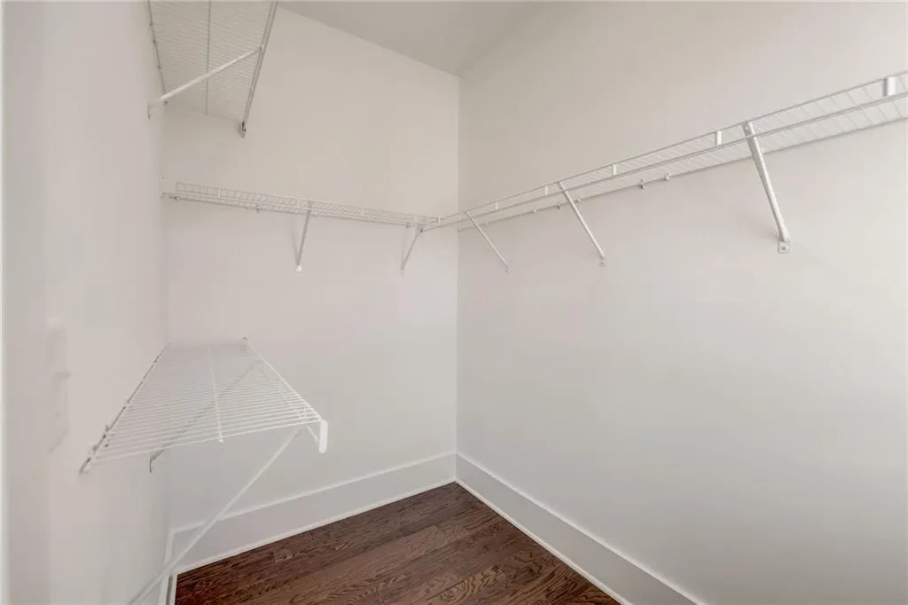 Walk in closet with dark wood-type flooring