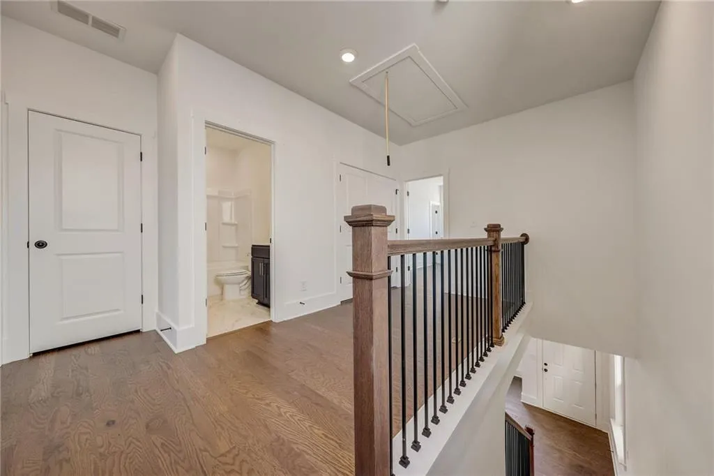 Corridor featuring attic access, an upstairs landing, dark wood-style flooring, and recessed lighting
