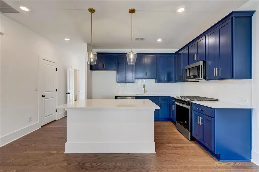 Kitchen with blue cabinetry, stainless steel appliances, tasteful backsplash, light countertops, and a kitchen island