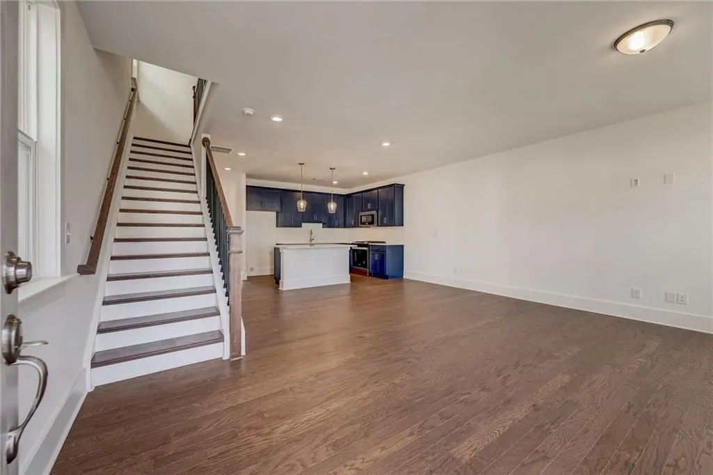Unfurnished living room with dark wood-type flooring, recessed lighting, and stairway