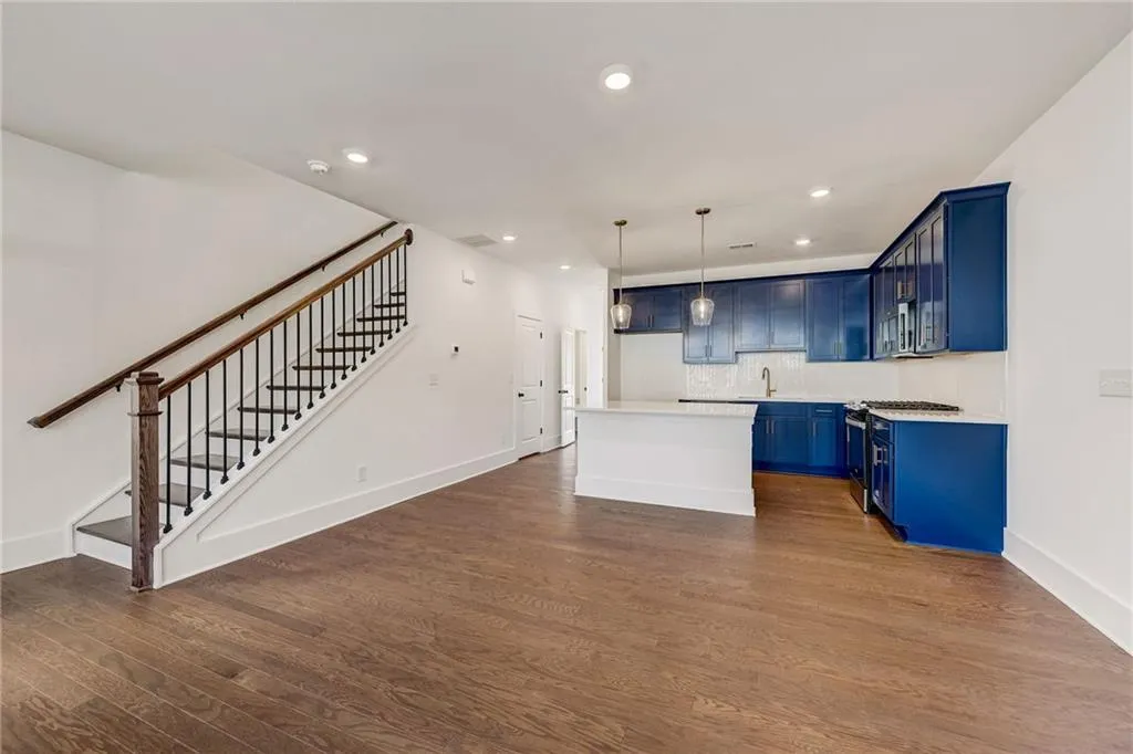 Kitchen featuring blue cabinets, recessed lighting, dark wood-style flooring, light countertops, and a kitchen island