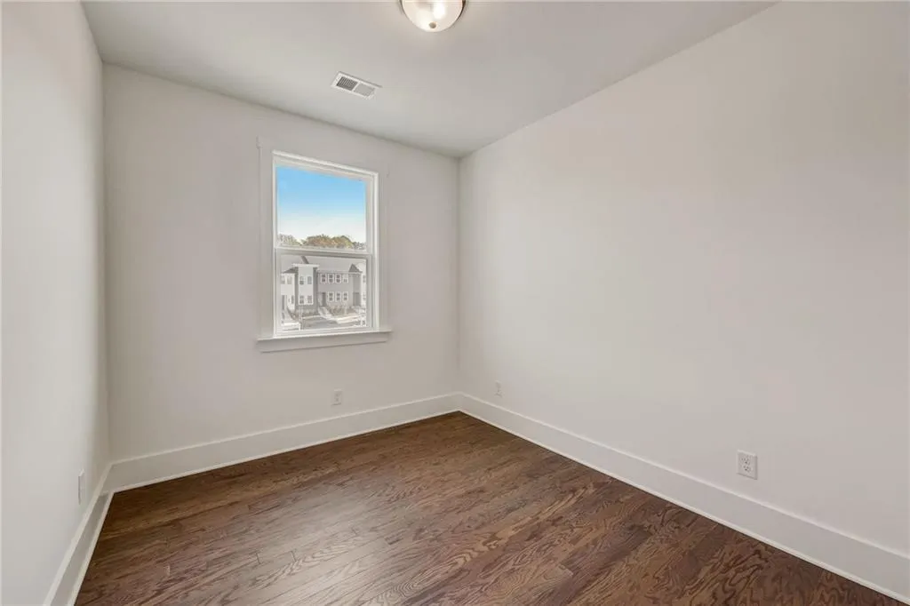 Spare room featuring dark wood-type flooring and baseboards
