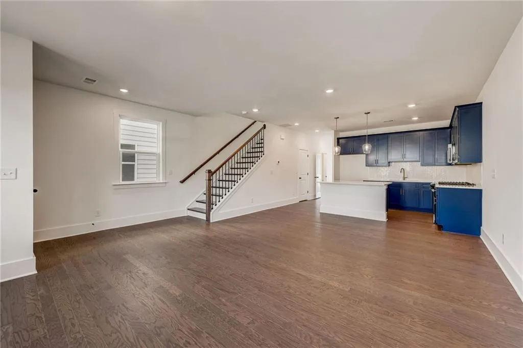 Unfurnished living room with dark wood finished floors, recessed lighting, and stairs