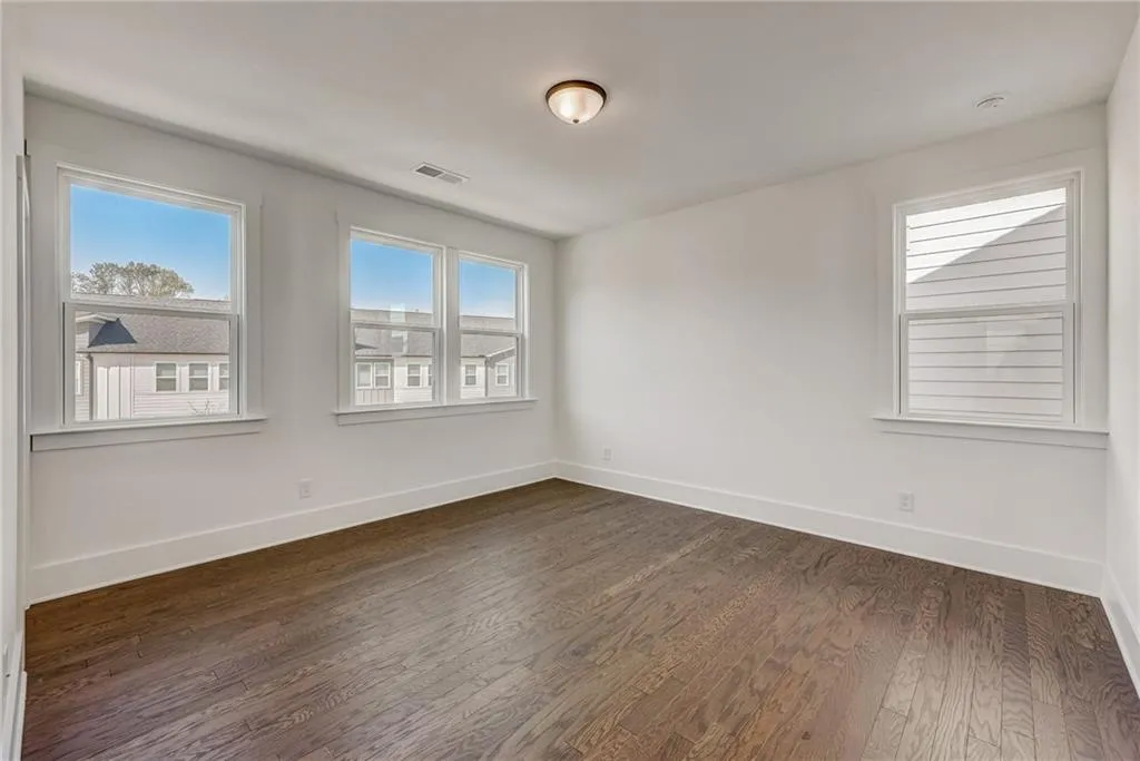 Empty room featuring dark wood-style floors and baseboards