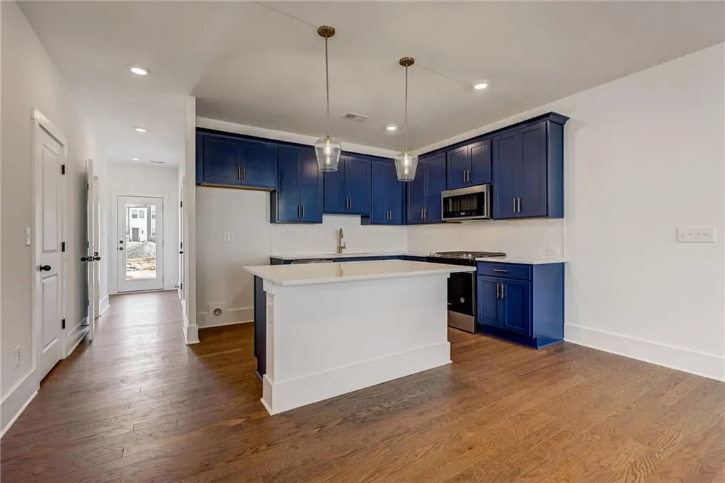 Kitchen with blue cabinets, stainless steel appliances, light countertops, dark wood-style floors, and recessed lighting