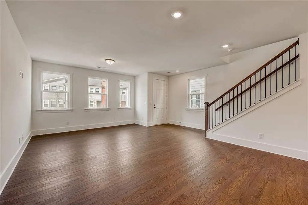 Unfurnished living room featuring stairs, dark wood-style flooring, and recessed lighting