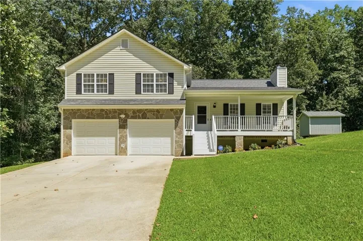 Two-story residence featuring a covered front porch, two-car garage, and a detached storage shed