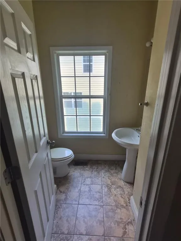 Dual pedestal sinks with ceramic basins, tile flooring, and a large multi-pane window providing natural light to this two-fixture bathroom space