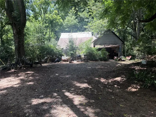 Rural property featuring two detached structures amidst mature trees