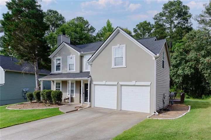 Contemporary-style residence featuring a two-car garage, covered porch entry, stucco and siding exterior, and a dark shingle roof