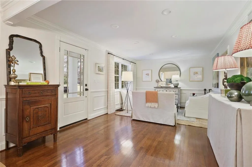 Foyer entrance with a decorative wall, wainscoting, dark wood finished floors, and crown molding