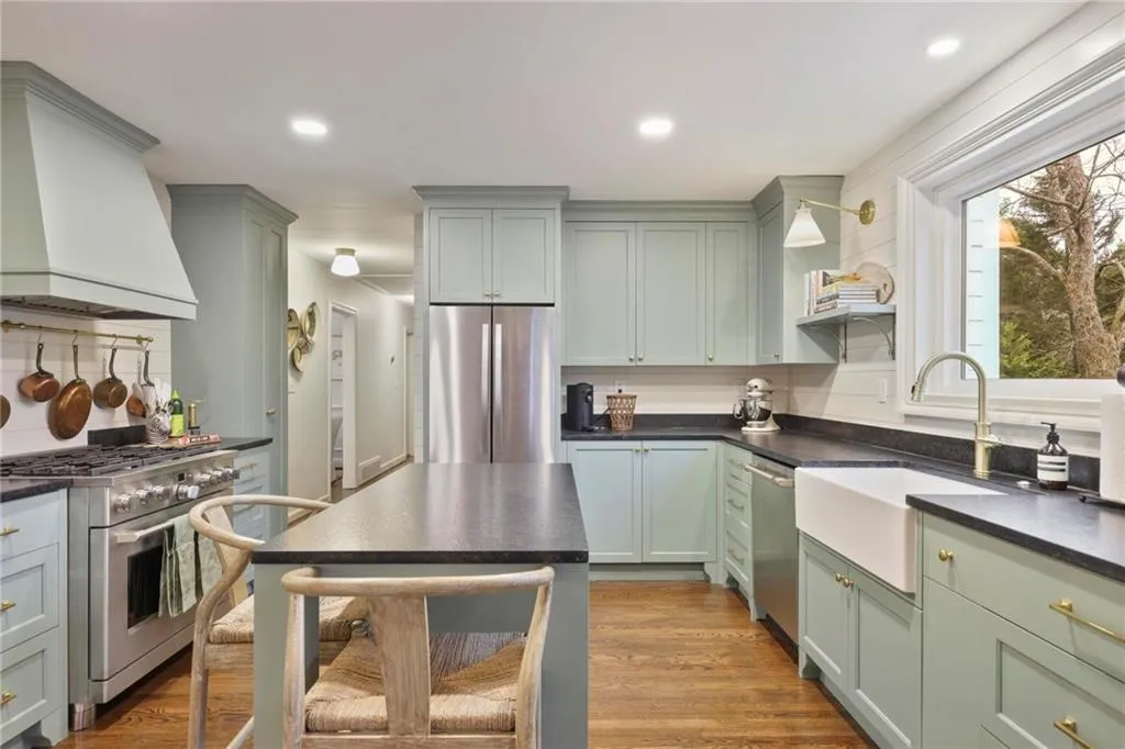Kitchen featuring stainless steel appliances, dark countertops, a sink, light wood-type flooring, and premium range hood