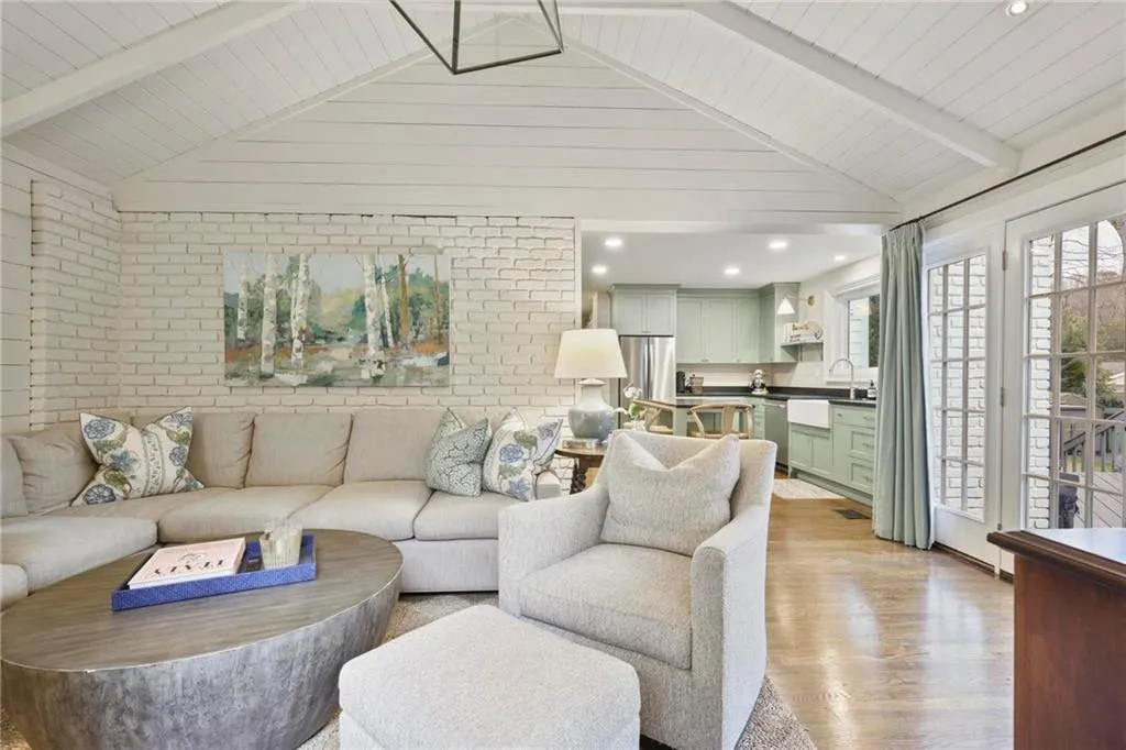 Living area featuring vaulted ceiling with beams, brick wall, recessed lighting, and light wood-style floors