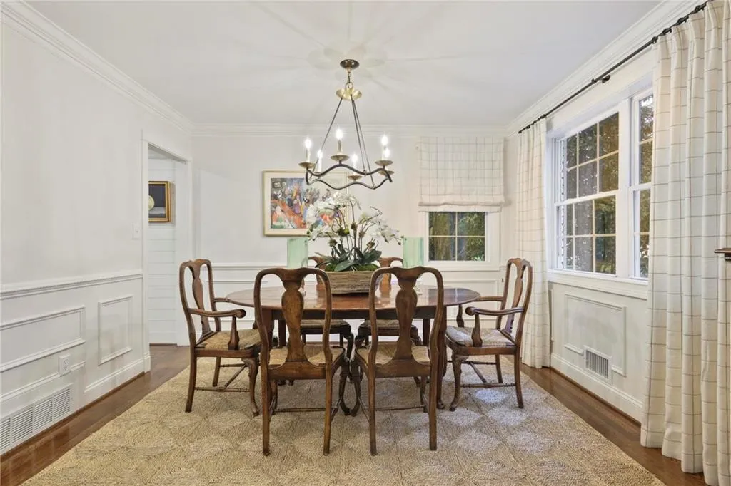 Dining room with an inviting chandelier, wood finished floors, visible vents, and crown molding