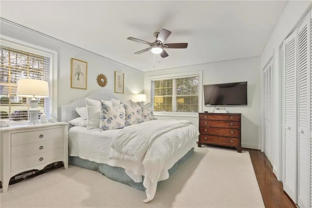 Bedroom with a ceiling fan, multiple windows, and wood finished floors