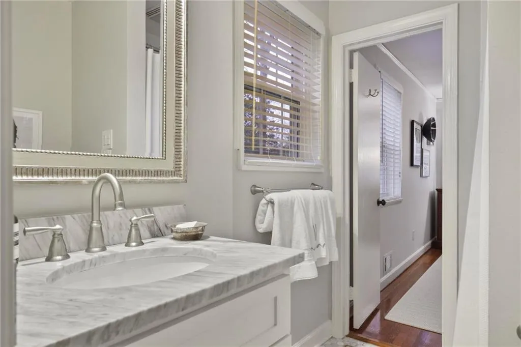Bathroom with visible vents, vanity, baseboards, and wood finished floors