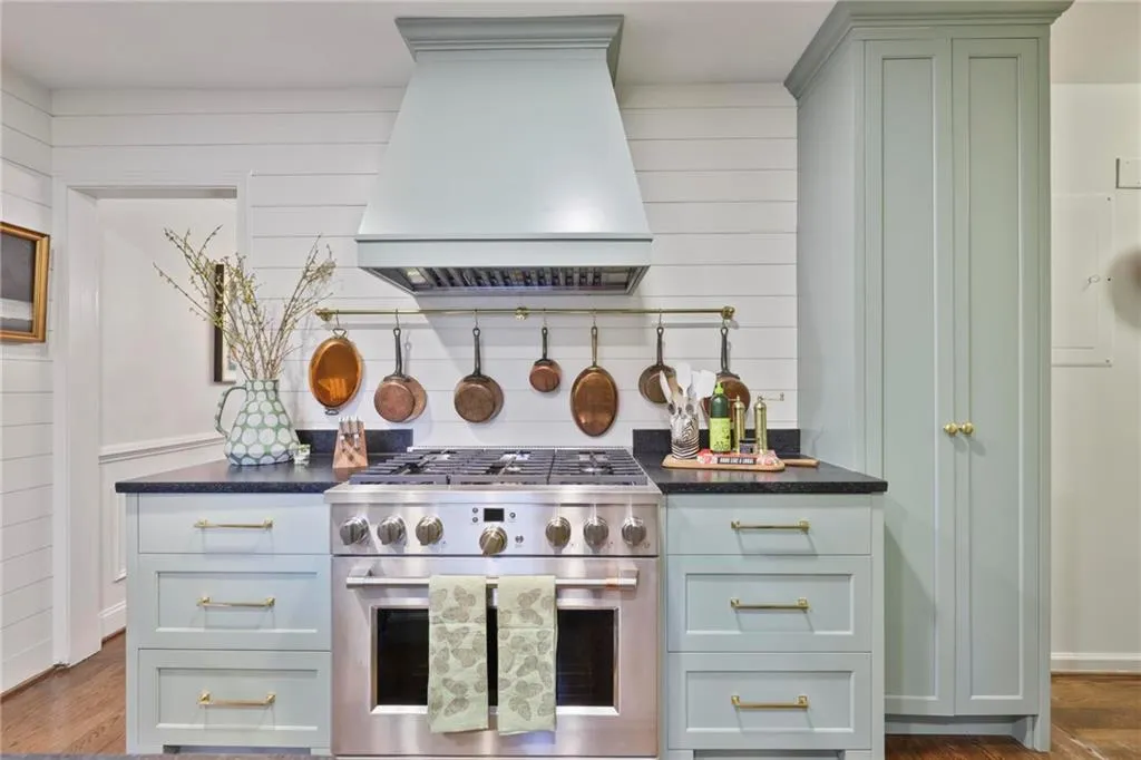 Kitchen featuring custom range hood, dark stone counters, high end range, and dark wood-type flooring