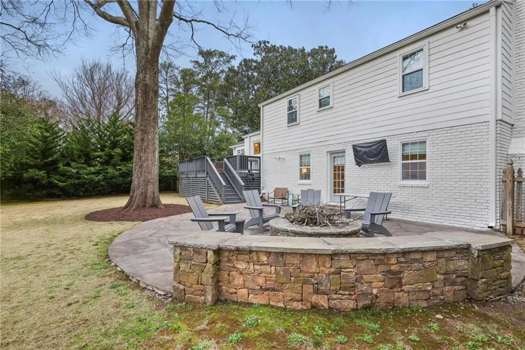 Back of house with a patio area, a wooden deck, a fire pit, and brick siding