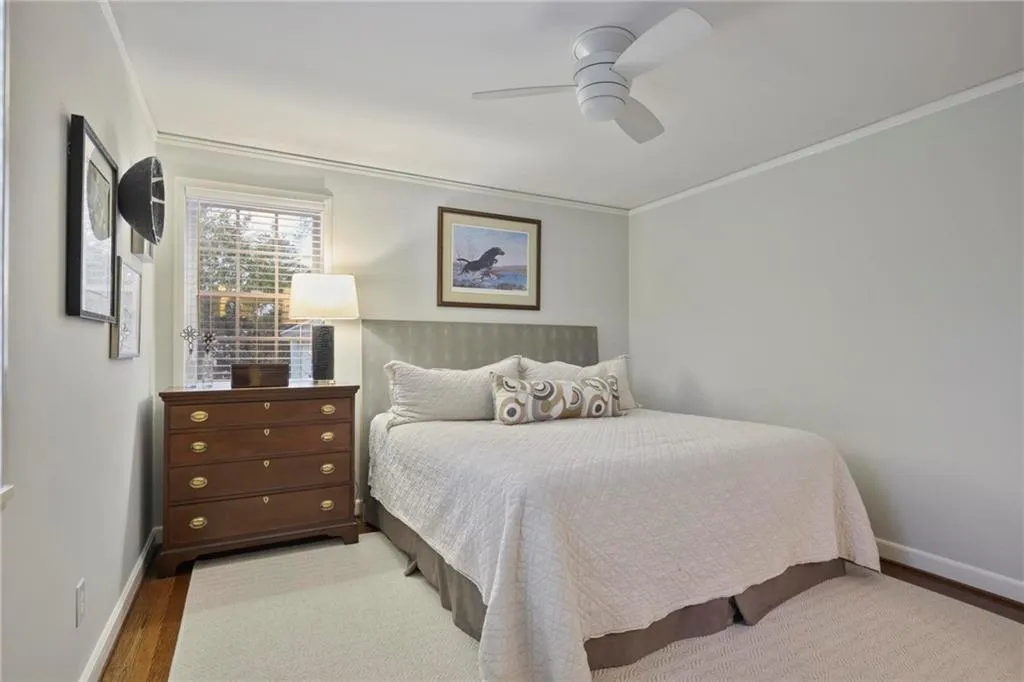 Bedroom featuring a ceiling fan, baseboards, ornamental molding, and wood finished floors