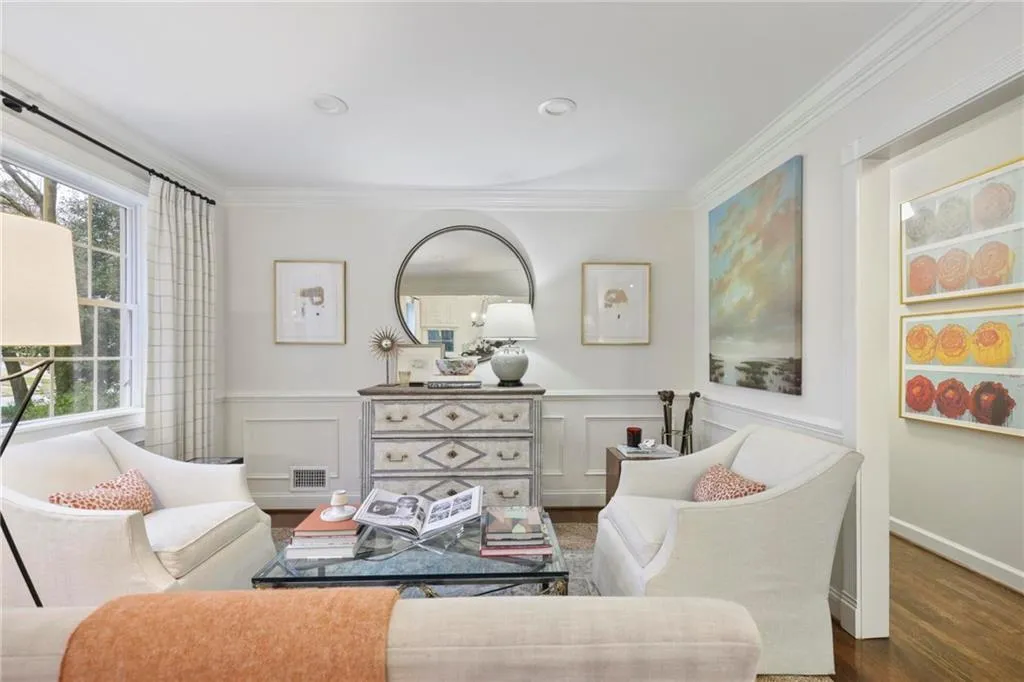 Living room with ornamental molding, a wainscoted wall, visible vents, and wood finished floors