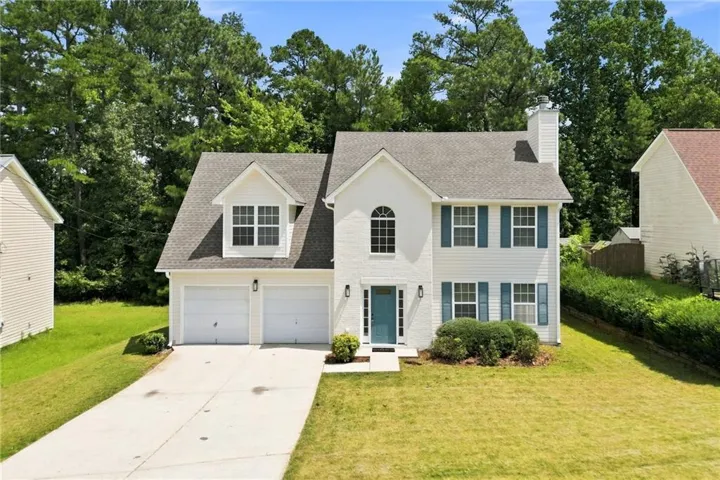 Two-story residence featuring a white facade, blue window shutters, and an arched entry window