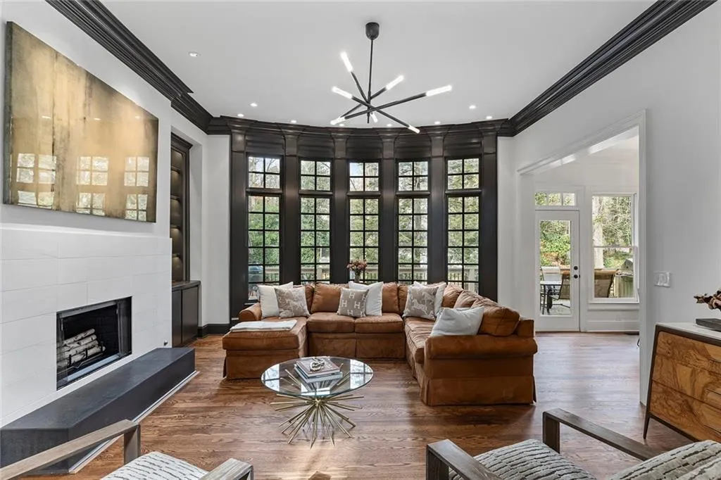 Living area with a chandelier, a fireplace with raised hearth, ornamental molding, and wood finished floors