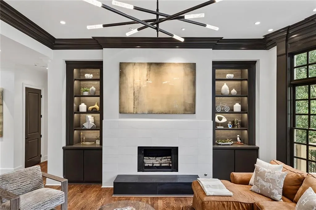 Living room featuring built in shelves, crown molding, wood finished floors, a fireplace, and recessed lighting