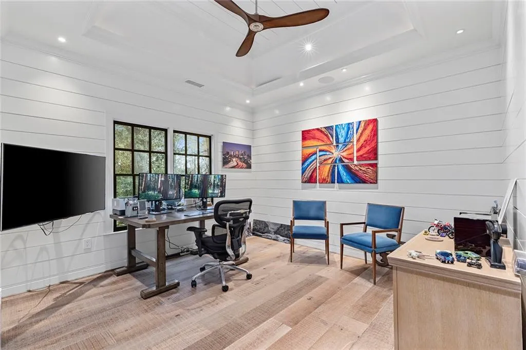 Office with a raised ceiling, wooden walls, ceiling fan, and recessed lighting